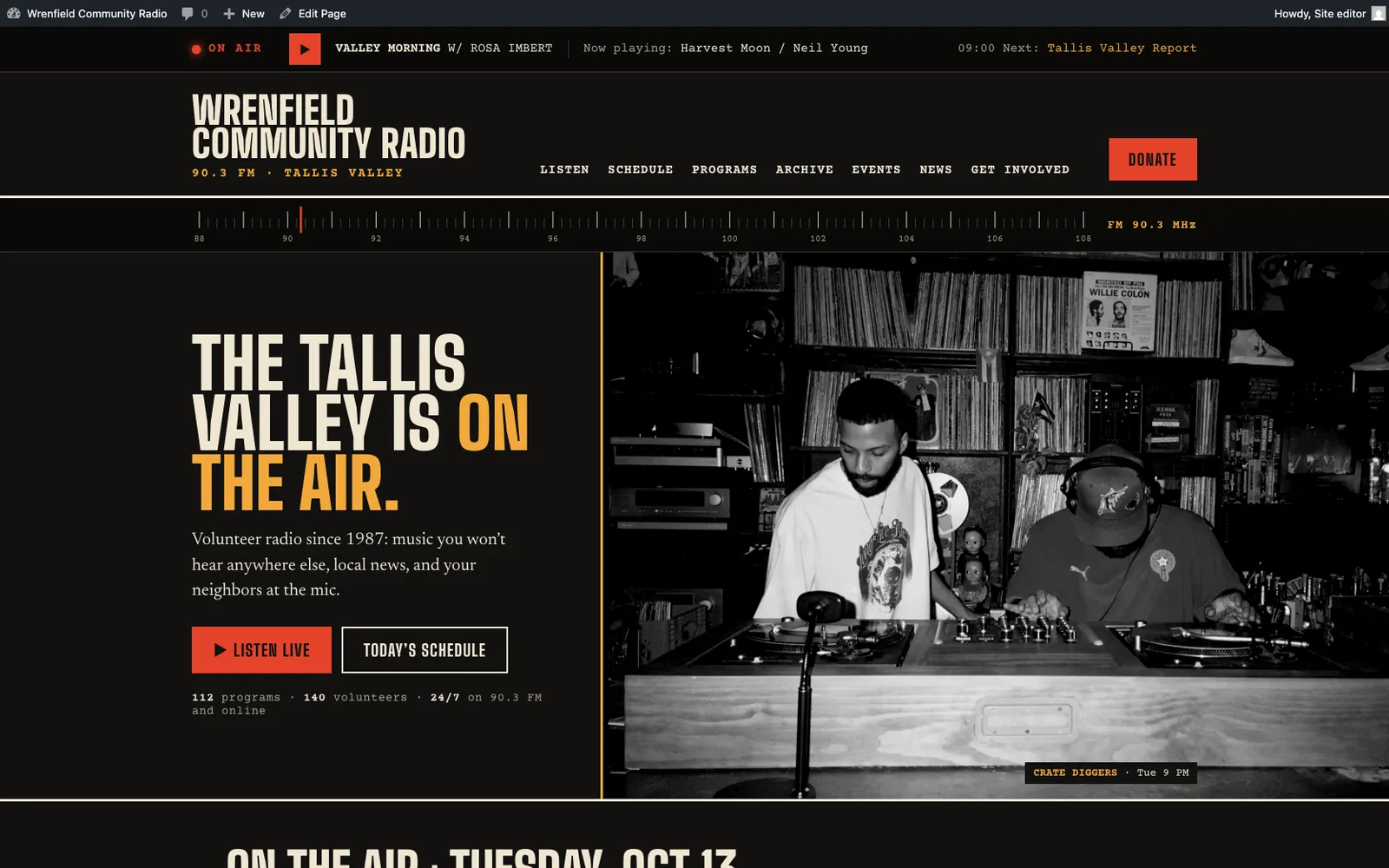 La homepage di Wrenfield Community Radio: una barra della diretta, il nome della radio, una scala FM, il titolo The Tallis Valley is on the air, i pulsanti Listen live e Today's schedule e una foto in bianco e nero di due DJ a una consolle di dischi.