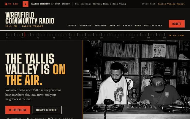 Homepage of Wrenfield Community Radio: an on-air bar, the headline The Tallis Valley is on the air, an FM tuning dial, and a black-and-white photograph of two DJs at a record console.